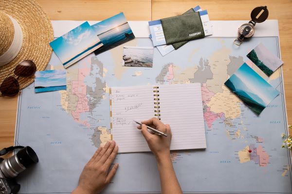 Persona planificando viaje con mapa, fotos y lista