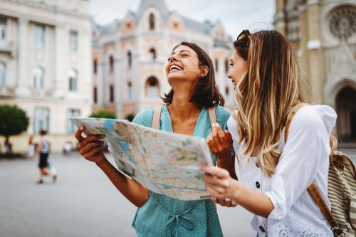 Dos muejres en sus vacaciones, felices viendo mapa turístico