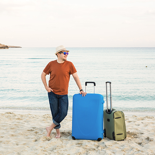 Hombre con maletas en la playa - preparar viaje