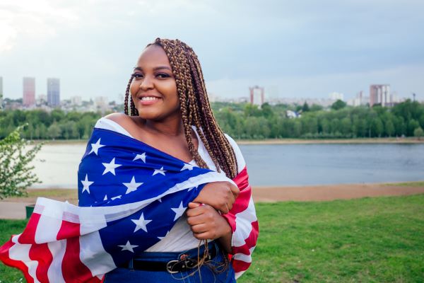Mujer feliz con bandera de Estados Unidos abrazándola