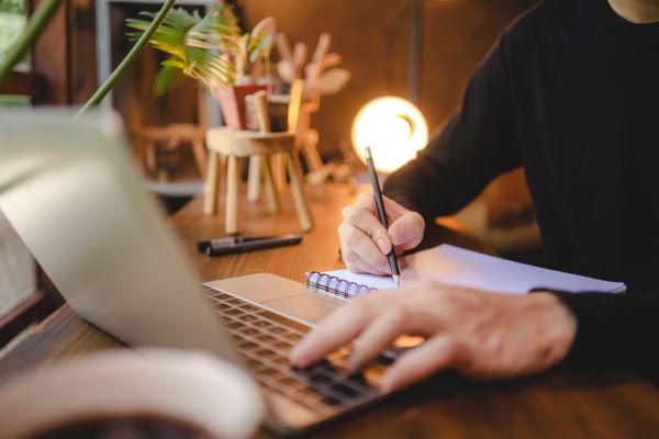Persona anotando consejos para la cita de pasaporte desde su laptop