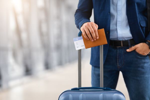 Hombre con maleta y pasaporte listo para viajar y trabajar en el exterior.
