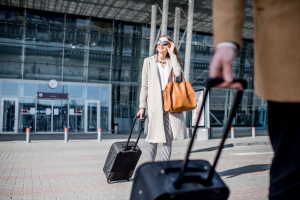 Mujer feliz con su maleta saliendo del aeropuerto para viajar después de gestionar visa