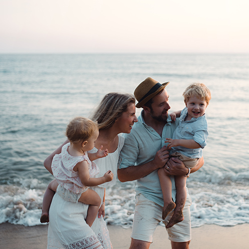 Familia sonriente y feliz en la playa durante sus vacaciones en familia,. Dos niños, una mujer y un hombre en la playa.