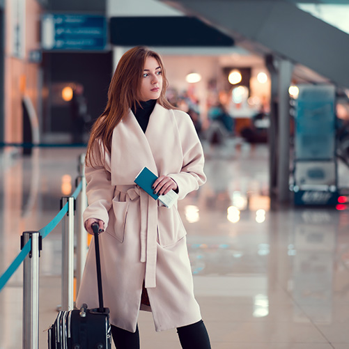 Mujer joven con pasaporte y equipaje, haciendo escala en aeropuerto de Canadá con visa de tránsito