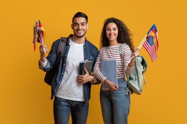 Hombre y mujer sosteniendo banderas internacionales, ambos representan futuros estudiantes que recibieron carta de aceptación