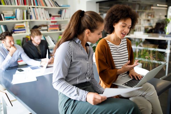 Dos mujeres viendo una computadora y conversando sobre sus estudios de perfil