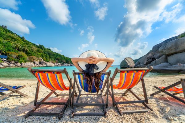 Mujer sentada en una silla disfrutando de una playa en un día soleado