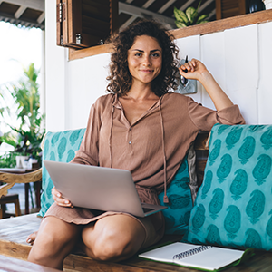 Mujer trabajando desde una playa con visa para nómadas digitales